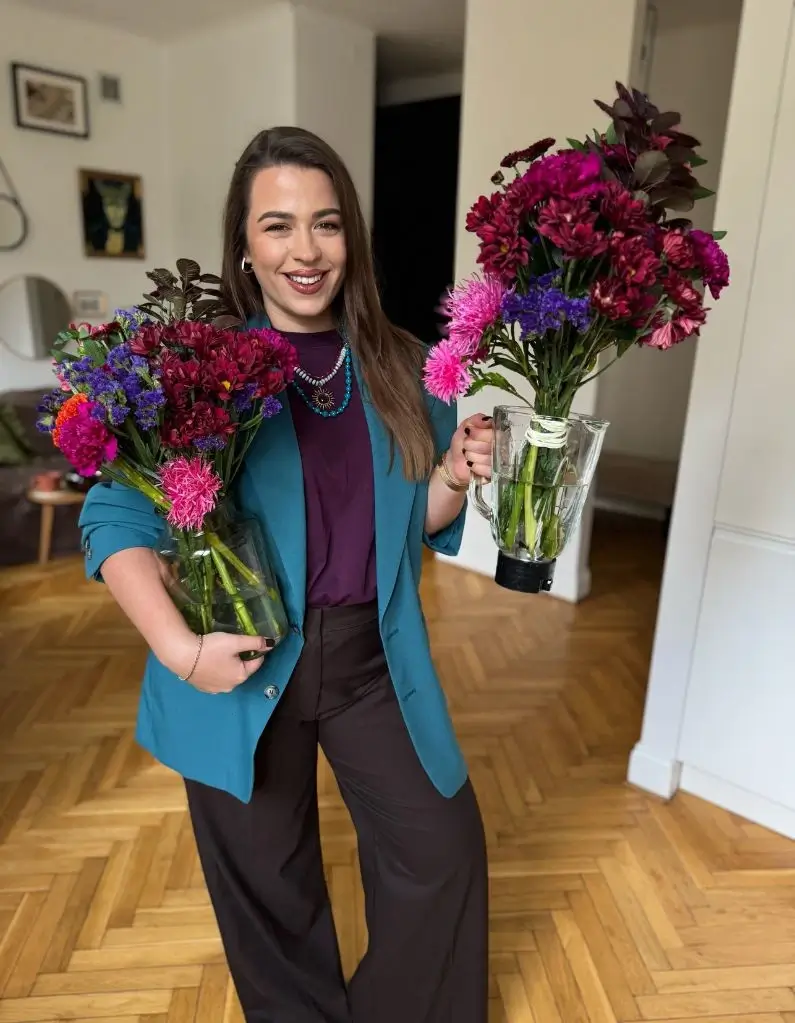Ewa gloria z dwoma pięknymi wazonami świeżych kwiatów w rękach.